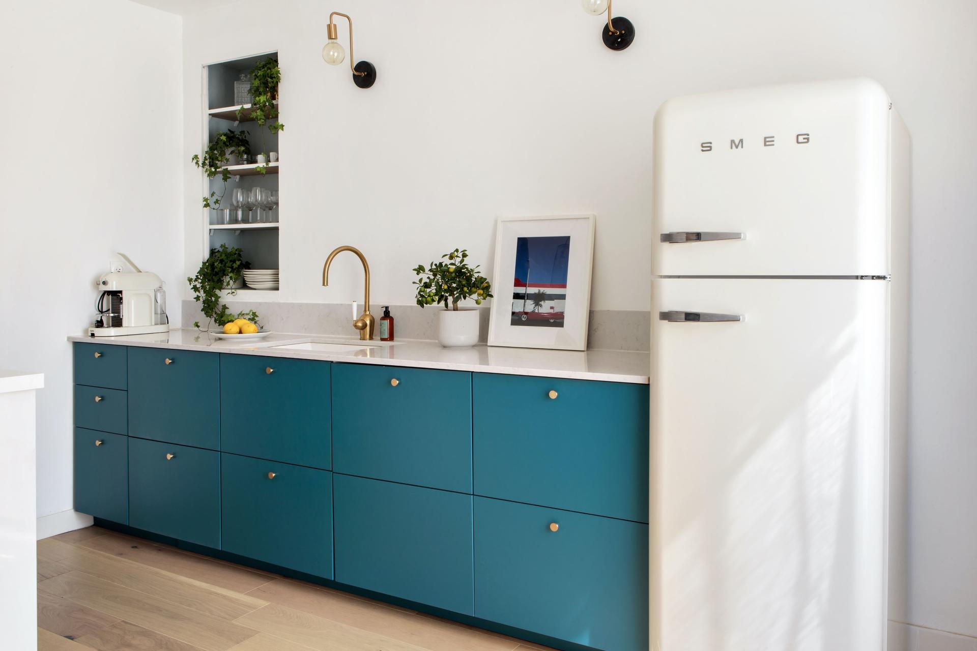 Moderne Küche nach Küchenrenovierung mit blauen Schränken, Marmor-Arbeitsplatte und weißem Retro-Kühlschrank.